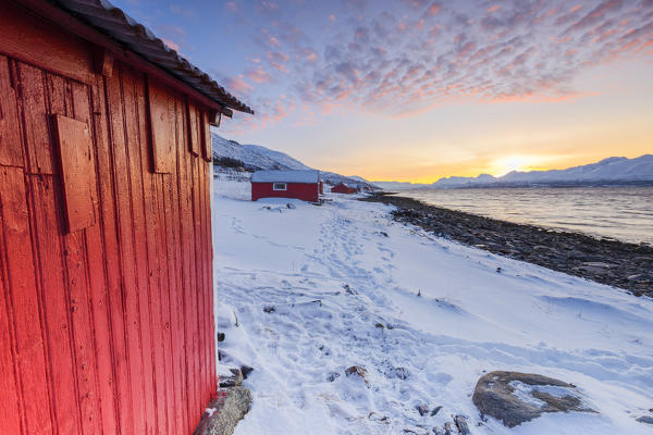 Sunset among the fishermen's houses overlooking the fjord. Nordmannvik, Kafjord, Lyngen Alps, Troms, Norway, Lapland, Europe.