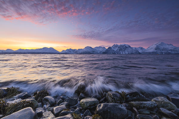 The waves breaking on the stones beach during sunset. Nordmannvik, Kafjord, Lyngen Alps, Troms, Norway, Lapland, Europe.