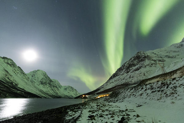 Northern Lights color the night sky lit up by the moon. Kjosenfjord, Lyngen Alps, Troms, Norway, Lapland, Europe.