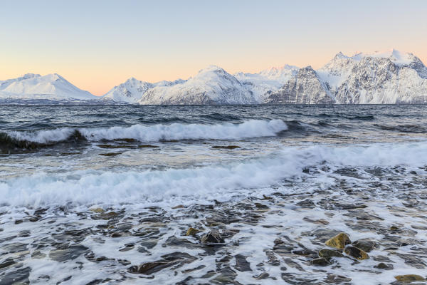 The waves breaking on a beach overlooking the Lyngen Alps during sunrise. Hammarvika, Lyngenfjord, Lyngen Alps, Troms, Norway, Lapland, Europe.