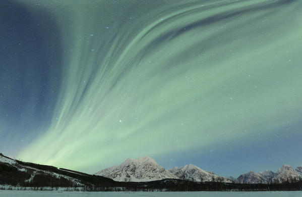 Aurora Borealis illuminates the landscape with views of the Lyngen Alps. Svensby, Ullsfjorden, Lyngen Alps, Troms, Norway, Lapland, Europe.
