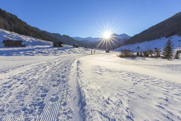 People strolling among the plateau huts, lit by the setting sun. Pfunds Tschey, Pfunds, Inntal, Tirol, Osterreich, Europe