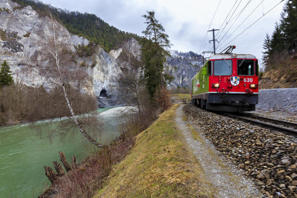 The Red Train passes along the Rhine River. Rhein Gorge(Ruinaulta), Flims, Imboden, Graubunden, Switzerland, Europe