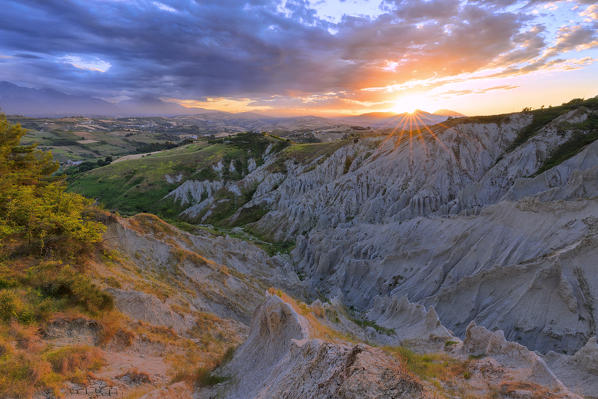Sun filters through the clouds during sunset illuminating the Calanchi of Atri, Abruzzo, Italy.