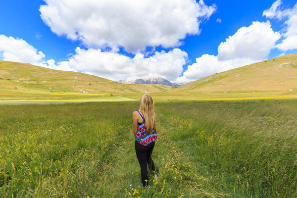 Young girl looks clouds above fields of Santo Stefano di Sessanio, Abruzzo, Italy.