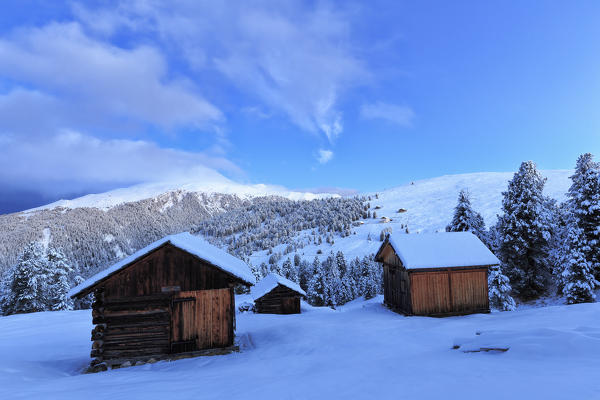 Old snow-covered huts during twilight.  Erbe Pass, Funes Valley, South Tyrol, Dolomites, Italy