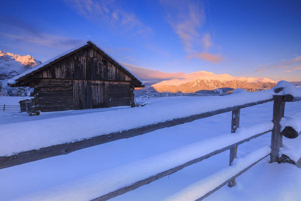 Old snow-covered hut during sunrise. Erbe Pass, Funes Valley, South Tyrol, Dolomites, Italy