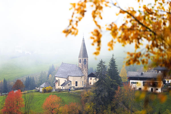 Church of Santa Magdalena in the autumn mist. Funes Valley, South Tyrol, Dolomites, Italy
