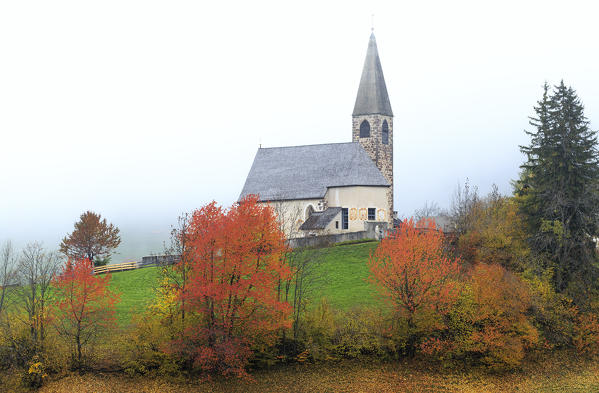 Church of Santa Magdalena in the autumn mist. Funes Valley, South Tyrol, Dolomites, Italy