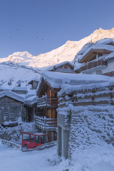 Elettric car parked in the historic center of Saas Fee with Alalinhorn, Alphubel and Täschhorn illuminated by sun. Saas Fee, Canton of Valais / Wallis, Switzerland.