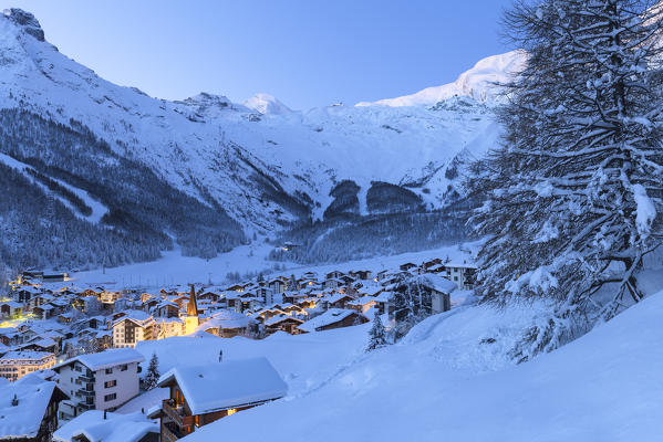 Lights on the church and the historic center of Saas Fee during twilight. Saas Fee, Canton of Valais / Wallis, Switzerland.