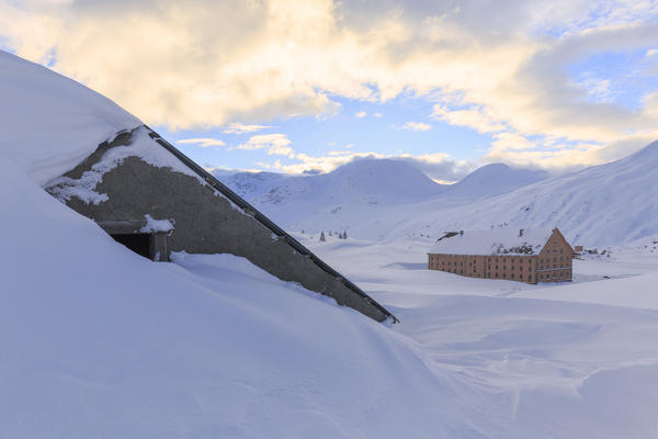 Hut submerged in the snow with the Simplon Pass hospice in the background. Simplon Pass, Canton of  Valais/Wallis, Switzerland.