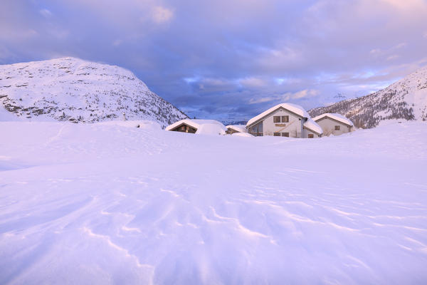 Snow shaped by the wind at some traditional huts at the Simplon Pass during the sunset. Simplon Pass, Canton of  Valais/Wallis, Switzerland.