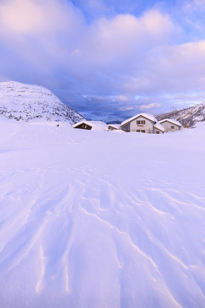 Snow shaped by the wind at some traditional huts at the Simplon Pass during the sunset. Simplon Pass, Canton of  Valais/Wallis, Switzerland.