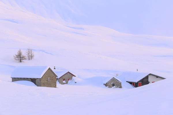 Huts partly submerged by a heavy snowfall to the Simplon Pass during  sunset. Simplon Pass, Canton of  Valais/Wallis, Switzerland.