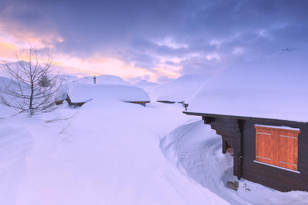 Huts partly submerged by a heavy snowfall to the Simplon Pass during  sunset. Simplon Pass, Canton of  Valais/Wallis, Switzerland.
