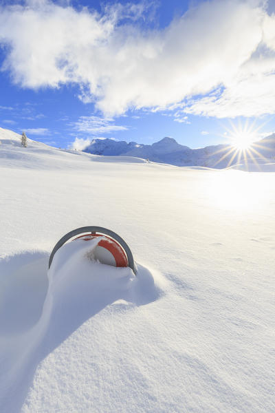The setting sun illuminates a road sign submerged in the snow. Simplon Pass, Canton of  Valais/Wallis, Switzerland.