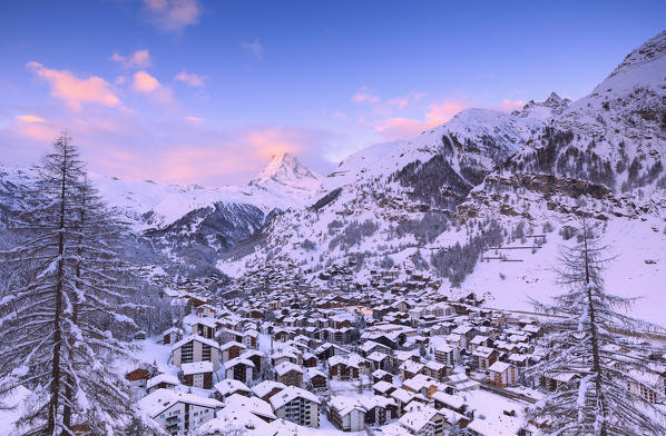 Sunrise on the village of Zermatt with the top of the Matterhorn hidden by a colored cloud. Zermatt, Canton of Valais / Wallis, Switzerland.