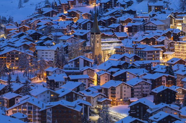 Church of Zermatt and buildings with the lights on during twilight. Zermatt, Canton of Valais / Wallis, Switzerland.