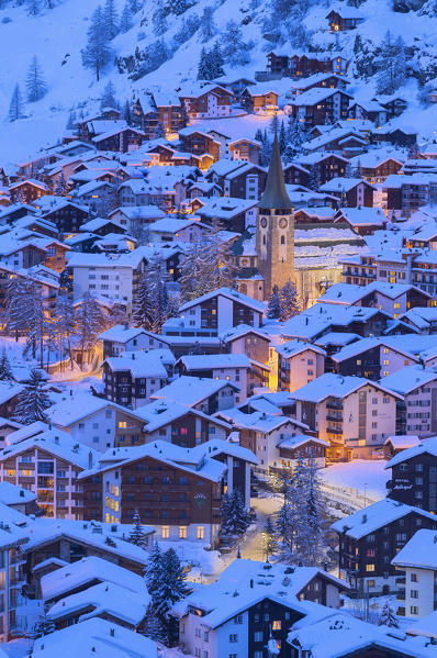 Church of Zermatt and buildings with the lights on during twilight. Zermatt, Canton of Valais / Wallis, Switzerland.