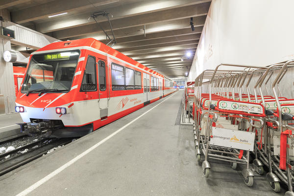 Train waiting to leave and luggage trolleys at Zermatt railway station, Canton of Valais / Wallis, Switzerland.