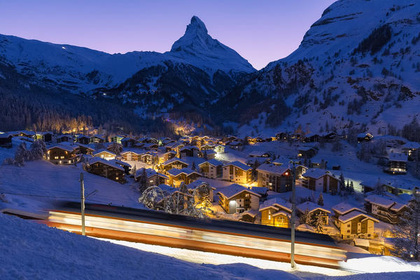 The train that goes up to the Gornergratt passes over the houses of Zermatt during twilight. Zermatt, Canton of Valais / Wallis, Switzerland.