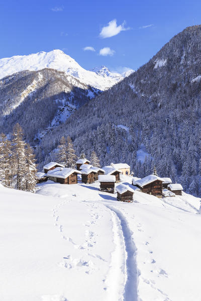 A trail in the snow leads to the traditional huts of  Blatten. Zermatt, Canton of Valais / Wallis, Switzerland.