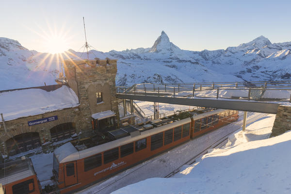 Red train stopped at the station of Gornergrat, illuminated by the setting sun. Gornergrat, Zermatt, Canton of Valais / Wallis, Switzerland.