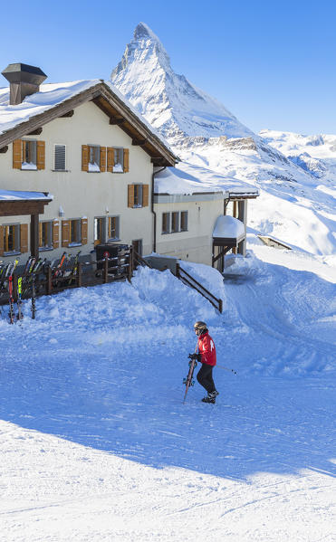 Skier walk in the snow to reach the restaurant with Matterhorn in the background. Riffelberg, Zermatt, Canton of Valais / Wallis, Switzerland.