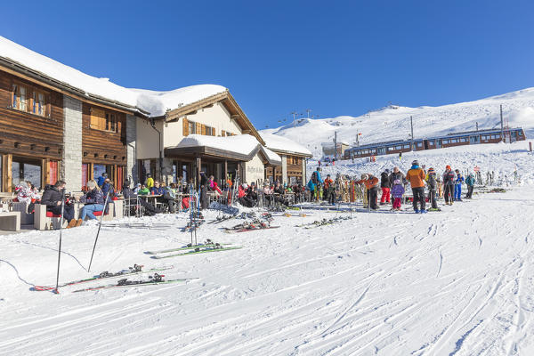 Restaurant full of customers with the train of Gornergrat stopped at the station. Riffelberg, Zermatt, Canton of Valais / Wallis, Switzerland.