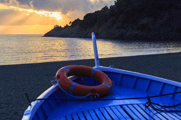 Boat on the beach of Bonassola with sunset on Madonnina della Punta Church. Bonassola, Liguria, Italy.