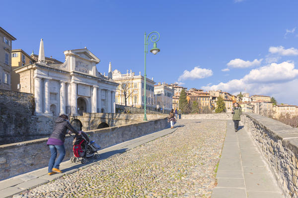 People walks  on the stone bridge to the Porta San Giacomo in Upper Town (Città Alta). Bergamo, Lombardy, Italy.