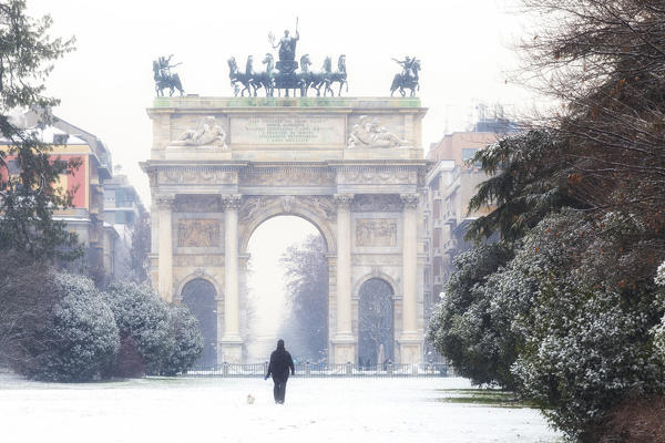 One person walks in the snow in front of Arch of Peace. Milan, Lombardy, Northern Italy, Italy.