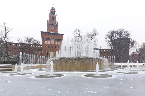A iced fountain and Sforzesco Castle after a snowfall. Milan, Lombardy, Northern Italy, Italy.
