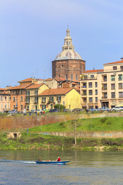 A boat navigates in the Ticino river with the Pavia Cathedral in the background. Pavia, Pavia province, Lombardy, Italy, Europe.