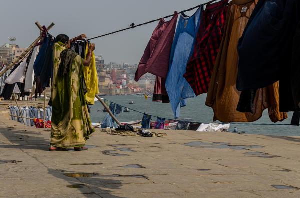 Varanasi, Uttar Pradesh, India. A woman hanging the clothes to dry on the Ghats.