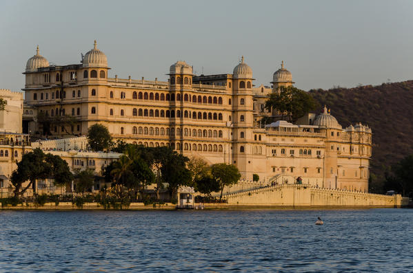 Udaipur, Rajasthan, India. The Udaipur City Palace at sunset seen from the shores of the Pichola Lake.