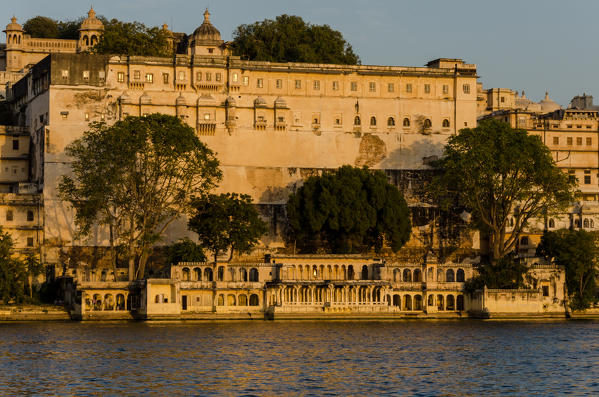 Udaipur, Rajasthan, India. The Udaipur City Palace at sunset seen from the shores of the Pichola Lake.