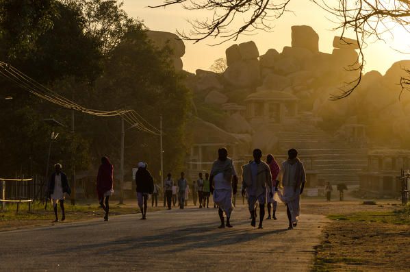 Hampi, Karnataka, India, Asia. Indian pilgrims walking the streets of Hampi at sunrise.