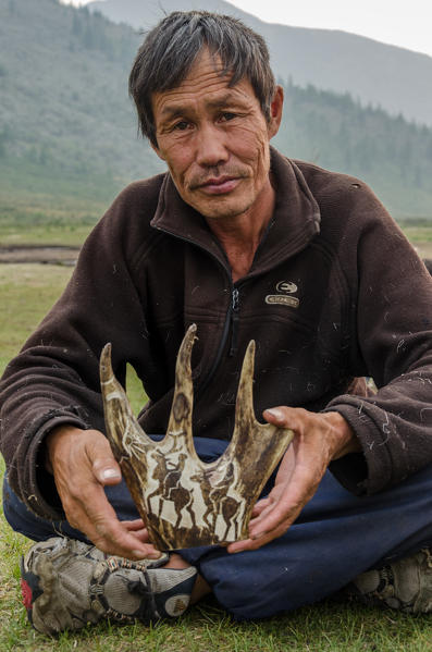A Tsaatan man with his artwork on a reindeer antler, Tsaatan Camp, Hovsgol Province, Northern Mongolia.