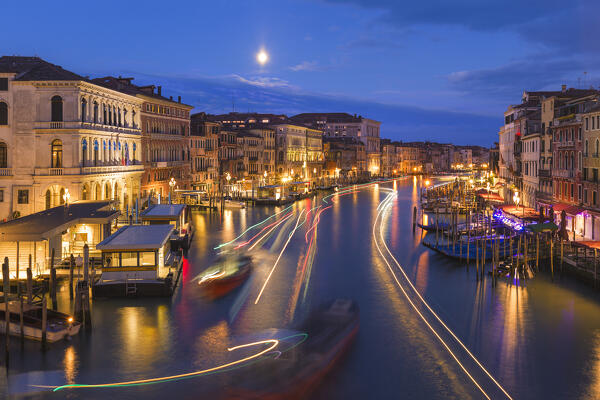 Dawn on Grand Canal (Canal Grande) from Rialto Bridge (Ponte di Rialto) with full moon and lights of boats. Venice, Veneto, Italy, Europe