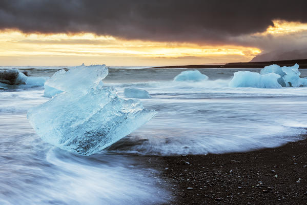 Jokulsarlon, eastern Iceland, Europe. Blocks of ice on the black beach in Jokulsarlon Glacier Lagoon during a sunset