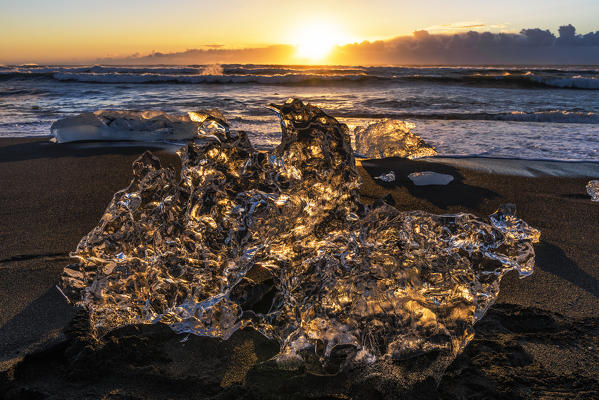Jokulsarlon glacier lagoon, Iceland. Sunlight reflections over a small black of ice on the shore.