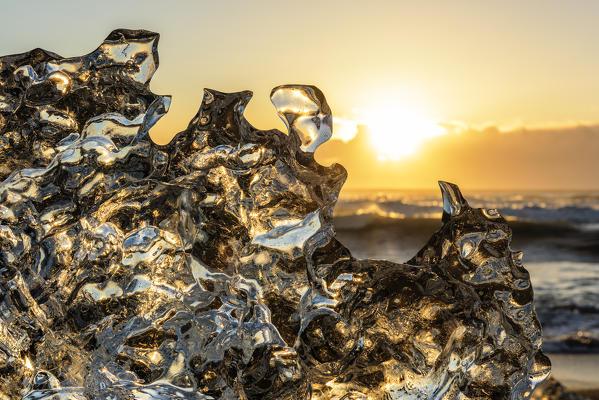 Jokulsarlon glacier lagoon, Iceland. Sunlight reflections over a small black of ice on the shore.