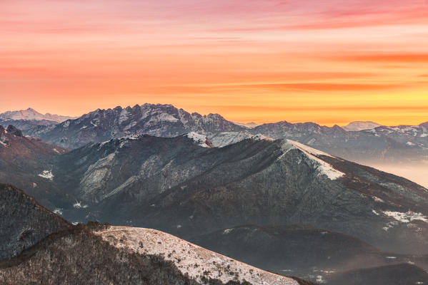 Overviewed of Resegone, Monte Rai and Cornizzolo peaks from Bollettone Mount and colourful sunrise sky in the background, Como province, Lombardy, Italy