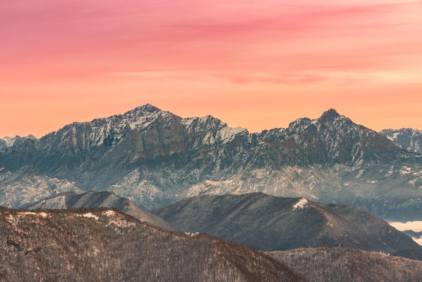 Overviewed of Grigna settentrionale and Grigna meridionale peaks from Bollettone Mount and colourful sunrise sky in the background, Como province, Lombardy, Italy