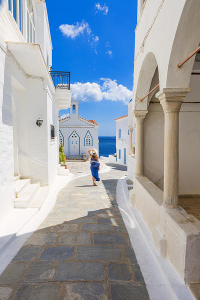 Young woman walking on the street that leads to the Church of St. Barbara, Andros, Cyclades archipelago, Greece, Europe (MR)