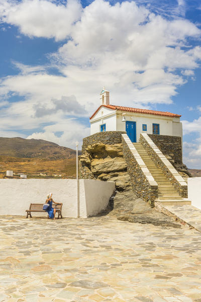 Tourist in a blue dress relaxing on a bech near St, Thalassini Church, Andros, Cyclades archipelago, Greece, Europe