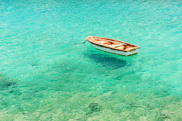 Wooden boat floating on the crystal and turquoise sea at Limeni, Mani region, Peloponnese, Greece, Europe