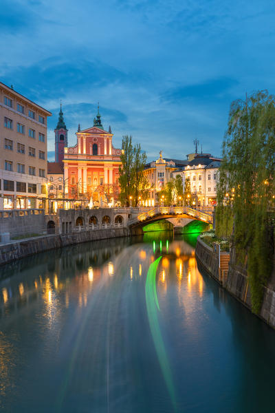 Light trail of a touristic boat and triple bridge lights reflected on Ljubljanica river. Ljubljiana, Osrednjeslovenska, Slovenia